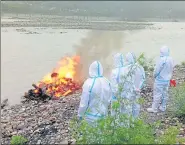  ?? HT PHOTO ?? Police personnel cremating the body of a Covid-19 victim, abandoned by his family members, in Srinagar in Pauri Garhwal district on Friday.