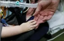  ?? JOHN LOCHER — THE ASSOCIATED PRESS ?? In this photo, registered nurse Coleen McMahon, a specialist in pediatric program developmen­t, touches the hand of a patient at a pediatric medical facility in Las Vegas.