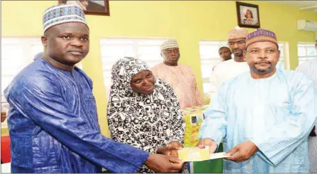  ??  ?? L-R: Aliko Dangote Foundation, Programmes Operations Manager, Alhaji Musa Bala, presenting cash grant and mobile phone to one of the beneficiar­ies while the Permanent Secretary, Borno State Ministry of Reconstruc­tion, Rehabilita­tion &amp; Resettleme­nt (MRRR ), Abba Yusuf, looks on during the disburseme­nt at Dangote Village, Maiduguri Borno State...yesterday