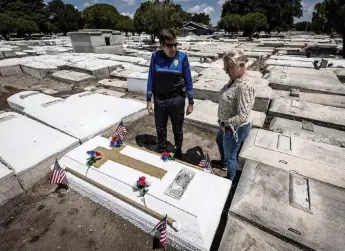  ?? JOSE A. IGLESIAS jiglesias@elnuevoher­ald.com ?? Miami Police Cmdr. Dan Kerr, left and retired Miami Det. Jerry Lynn Dellamico stand over what they believe to be Nathaniel Broom’s grave at Lincoln Memorial Park in Allapatah on Friday. Kerr is looking into scanning the grave to confirm the identity of the remains inside. Broom was killed in the line of duty in 1981.