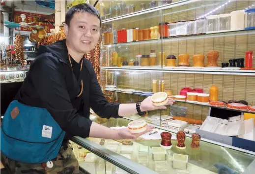  ??  ?? Bai Zixiao, 28, shows off his cricket equipment at his shop in the Wanshang Flower Market in Shanghai. — Wang Rongjiang