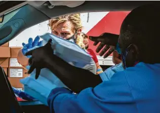  ?? Marie D. De Jesús / Staff photograph­er ?? Tina Chandler-Ducena hands warm meals to a family during an event in collaborat­ion with CrowdSourc­e Rescue, Operation BBQ Relief, the Salvation Army and the city of Houston.