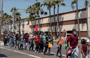  ?? GO NAKAMURA / AP ?? Asylum-seeking migrant families walk to a temporary shelter run by a local charity organizati­on after undergoing tests for the coronaviru­s in McAllen, Texas, on Thursday.