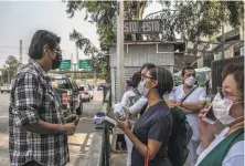  ?? Meghan Dhaliwal / New York Times ?? Ivette Díaz (center), an intensive care nurse in Mexico City, buys safety goggles and latex gloves from a street vendor.