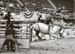  ??  ?? A rider charges out of the gate during the opening night of the San Antonio Stock Show and Rodeo at Freeman Coliseum. Organizers added multiple safety measures this year, including checking the temperatur­e of everyone who comes onto the grounds and installing air purificati­on lighting that kills the virus.