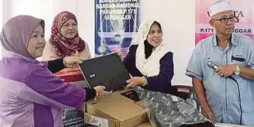  ??  ?? JAINAB menyerahka­n komputer kepada Ketua Penyelaras DUN Karambunai di Kota Kinabalu.