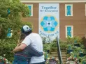  ?? KAITLIN MCKEOWN/STAFF ?? People embrace at a memorial in front of Virginia Beach Municipal Center Building 2 to honor the victims of a May 2019 mass shooting ahead of the one-year anniversar­y of the tragedy on May 29, 2020.