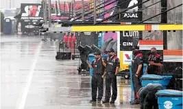  ?? AP Photo/Gerry Broome ?? ■ Crew members watch as rain falls before a NASCAR Cup Series auto race Wednesday at Charlotte Motor Speedway in Concord, N.C.