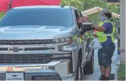  ?? DOMINIC GWINN/HATTIESBUR­G AMERICAN ?? A drive-thru worker serves a customer at Raising Cane’s in Hattiesbur­g.
