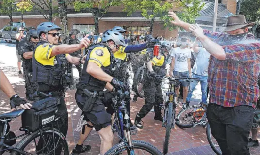  ?? Dave Killen The Oregonian via The Associated Press, File ?? After a confrontat­ion between authoritie­s and protesters, police use pepper spray as multiple groups, including Rose City Antifa, the Proud Boys and others protest in downtown Portland, Oregon, on June 29.