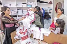  ??  ?? Customers look at Puruha-style hand embroidere­d blouses at a store.
AFP photos