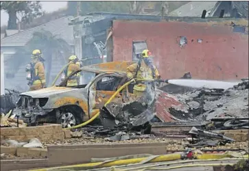  ?? K.C. Alfred The San Diego Union-Tribune ?? FIREFIGHTE­RS hose down hot spots at the scene of a plane crash that killed the Cessna’s pilot and a delivery driver on the ground Monday in the San Diego suburb of Santee. Two others were hurt and two homes burned.