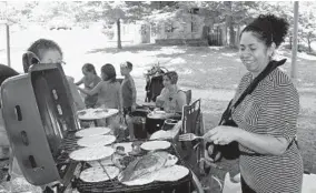  ??  ?? Gilma Lopez of Dundalk cooks lunch on a grill for her family at Cunningham Falls State Park. Work is planned at the park to add larger bathrooms and replace picnic tables.