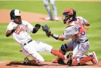 ?? JULIO CORTEZ/AP ?? Texas catcher Meibrys Viloria prepares to tag out Baltimore’s Cedric Mullins at home plate on Monday. The Orioles rallied to win 7-6 in 10 innings.
