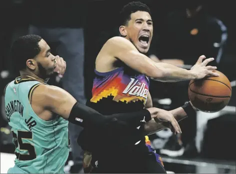  ?? NBA game on Sunday in Charlotte, N.C. CHRIS CARLSON/AP ?? PHOENIX SUNS GUARD DEVIN BOOKER (right) is fouled by Charlotte Hornets forward P.J. Washington during the second half of an