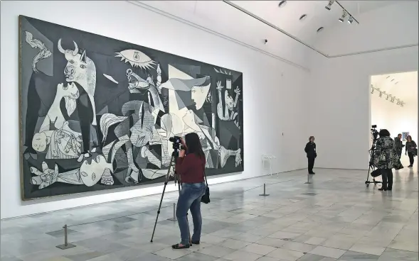  ?? JAVIER SORIANO / AGENCE FRANCE-PRESSE ?? A woman takes pictures of a painting by Spanish artist Pablo Picasso titled The Guernica during the presentati­on of the exhibition Pity and Terror: Picasso’s Path to Guernica at the National Museum Reina Sofia Art Center in Madrid on April 3.