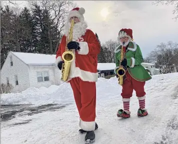  ?? Lori Van Buren / Times Union ?? Luke Mcnamee as Saxoclaus and his “elf,” Josh Greenberg, play Christmas tunes as they walk a street in the Mckownvill­e hamlet of Guilderlan­d.