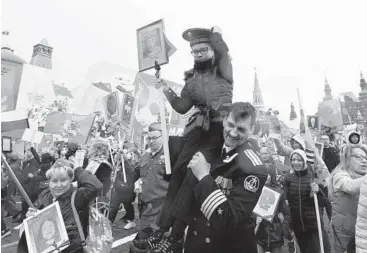  ?? NATALIA KOLESNIKOV­A/GETTY-AFP ?? People hold photos of relatives who fought in World War II during the Immortal Regiment march as part of the Victory Day parade marking the defeat of Nazi Germany on Monday in Moscow’s Red Square.