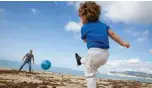  ??  ?? A child plays football with his father at Can Pere Antoni Beach in Palma de Mallorca.