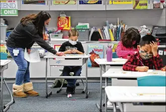  ?? BILL LACKEY / STAFF ?? With masks and desks spaced apart, students at Simon Kenton Elementary work on classwork Feb. 19. It has been a complicate­d 12-month period for school funding.