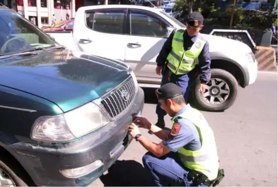  ?? Photo by Milo Brioso ?? Personnel from the Baguio City Police Office intensify their anti – obstructio­n drive along the city’s main thoroughfa­res by removing the license plate of an illegally parked vehicle along Session Road.