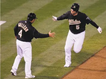  ?? Stephen Lam / The Chronicle 2009 ?? Matt Holliday (right) shares a high-five with third-base coach Mike Gallego after tying the game with a grand slam during the eighth inning of the A’s record-setting win over the Twins in 2009.