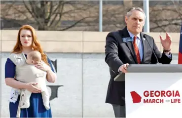  ?? NATRICE MILLER/THE ATLANTA JOURNAL-CONSTITUTI­ON/TNS ?? State Rep. Lauren Daniel, R-Locust Grove, left, holds her baby, Zane, as state Sen. Ed Setzler, R-Acworth, speaks during an antiaborti­on “March for Life” rally in February.