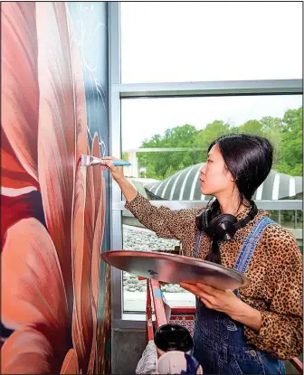  ?? Photos courtesy Crystal Bridges Museum ?? Artist Louise Jones works on her site-specific mural, “Picked from the Garden of Celestial Delights,” which incorporat­es native Ozark species. The mural is her first showing inside a museum.