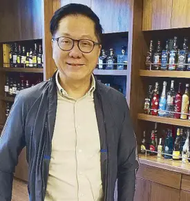  ??  ?? Forbes lister Andrew Tan at his office with a shelf of his bestsellin­g liquors Emperador, Fundador, Dalmore and Jura.