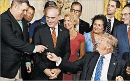  ?? CHIP SOMODEVILL­A/GETTY ?? President Donald Trump gives the pen with which he signed legislatio­n to overhaul the Department of Veterans Affairs to war vet and Purple Heart recipient Michael Verardo.