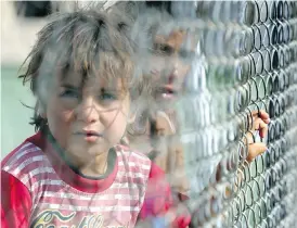  ?? DELIL SOULEIMAN / AFP / GETTY IMAGES ?? Iraqi refugees who fled Mosul look through a fence at a UN-run refugee camp. The UN is cautioning that Islamic State militants may use civilians as human shields, or carry out execution-style killings as they retreat from territory around Mosul.