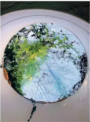  ?? FOTO: MARKUS LUIGS ?? Blasenförm­ige und teils überwucher­te Fenster lassen Licht ein. Gabi Luigs inszeniert sie in einem kreisrunde­n Spiegel wie eine Fotografie.