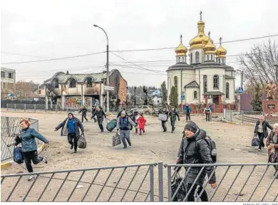  ?? ROMAN PILIPEY / EFE ?? Ciudadanos ucranianos cruzando ayer una carretera en su huida de la ciudad de Irpin, cercana a Kiev.