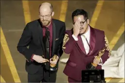  ?? Photo credit ?? Daniel Scheinert (left) and Daniel Kwan accept the award for best original screenplay for “Everything Everywhere All at Once” at the Oscars on Sunday at the Dolby Theatre in Los Angeles.