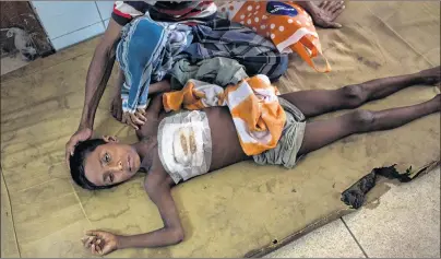  ?? AP PHOTO ?? Shoabib, 7, lies on the floor next to his father at Sadar Hospital in Cox’s Bazar, Bangladesh, Sunday. Shoabib got a bullet injury on the chest when Myanmar soldiers attacked his village.