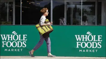  ?? NAM Y. HUH / ASSOCIATED PRESS ?? A shopper leaves a Whole Foods Market in the Chicago suburb of Northbrook, Ill., on Saturday. Amazon’s pending $13.7 billion buyout of the Austin organic grocer is expected to shake up the industry.