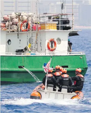  ??  ?? A United States Coast Guard team prepares to inspect an American fishing vessel off the coast of Honolulu in March. Government officials can tell owners to honour contracts and pay their workers, but have no authority over the amount paid, said one...