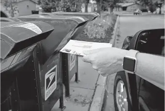  ?? ASSOCIATED PRESS FILE PHOTO] [NATI HARNIK/ ?? A person drops applicatio­ns for mail-in-ballots into a mailbox Aug. 18 in Omaha, Neb.