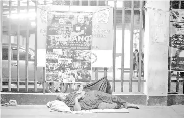  ??  ?? File photo shows a homeless woman sleeping in front of a government’s ‘War on Drugs’ campaign poster in Manila. — AFP photo