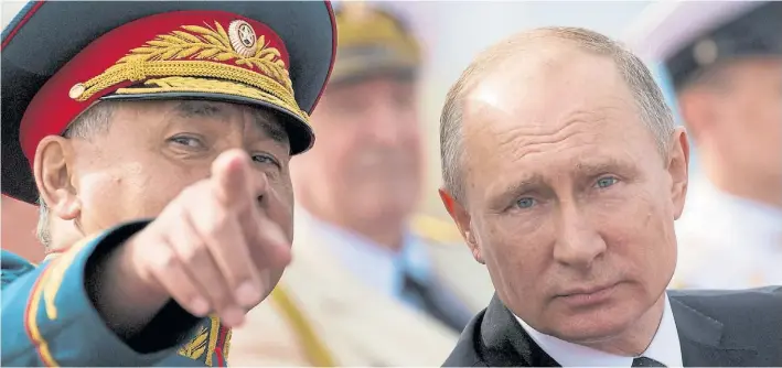  ?? AP ?? Liderazgo moscovita. El presidente Putin escucha a su ministro de Defensa, Sergei Shoigu, durante un desfile militar, ayer en San Petersburg­o, para celebrar el Día de la Armada.