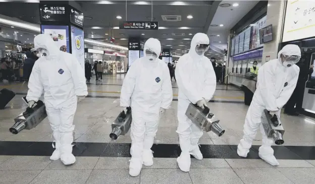  ??  ?? 0 Health workers wearing protective gear at a bus terminal in Gwangju spray disinfecta­nt as part of efforts to prevent the spread of a new virus which originated in Wuhan