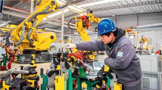  ?? ?? A worker is busy at a production line for auto parts in Huzhou, Zhejiang Province in east China, on 8 January 2023