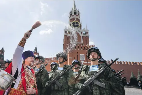  ?? ALEXANDER ZEMLIANICH­ENKO / THE ASSOCIATED PRESS FILES ?? A Russian Orthodox priest blesses paratroope­rs in Red Square in Moscow on Aug. 2. The Russian military says major war games, the Zapad (West) 2017 manoeuvres, set for this month will not threaten anyone, but keeping Western observers out has NATO...