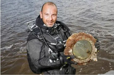  ?? Foto: dpa/Axel Heimken ?? Der Wracktauch­er Andi Peters steht in der Nordsee mit einem Fund aus einem Schiffswra­ck.