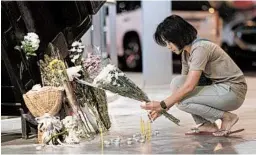  ?? WASON WANICHAKOR­N/AP ?? A woman lights a candle during a memorial service on Sunday at Terminal 21 Korat mall in Nakhon Ratchasima, Thailand. A mass shooting in the city left 29 dead.