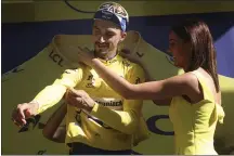  ?? THIBAULT CAMUS — THE ASSOCIATED PRESS ?? France’s Julian Alaphilipp­e puts on the overall leader’s yellow jersey on the podium following Wednesday’s 17th stage of the Tour de France.