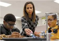  ??  ?? Left: Landtroop picks up a sample to help seventhgra­ders Cleavon Smith Jr., left, and Takwon Ragland on Friday during their lab at Orchard Knob Middle School.