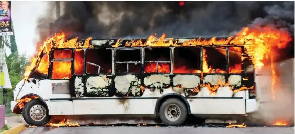  ??  ?? Hellfire: A bus is set ablaze amid the carnage which left eight dead as bungling police were hopelessly outgunned by the drug gang