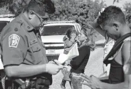  ?? Jerry Lara / San Antonio Express-News ?? Hondurans Jeny Patricia Figueroa Fernandez, 27, and daughter Dolores, 3, wait as Border Patrol Agent Christian Alvarez interviews other migrants.
