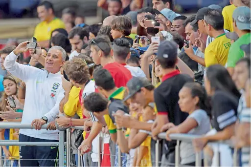  ?? — AFP ?? Brazil’s coach Tite (left) poses with fans after a training session at the Morumbi stadium in Sao Paulo, Brazil.